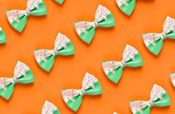 Colorful hair bow pattern on orange background, flat lay, top view