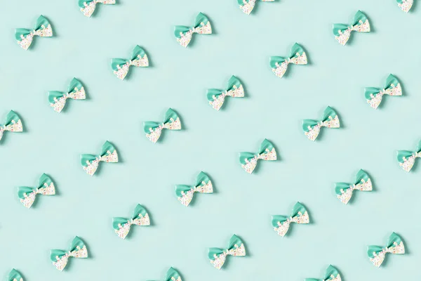 Colorful hair bow pattern on pastel blue background, flat lay, top view