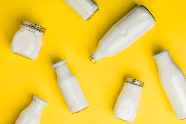 Verschiedene Flaschen Milch auf gelbem Hintergrund — Stockfoto