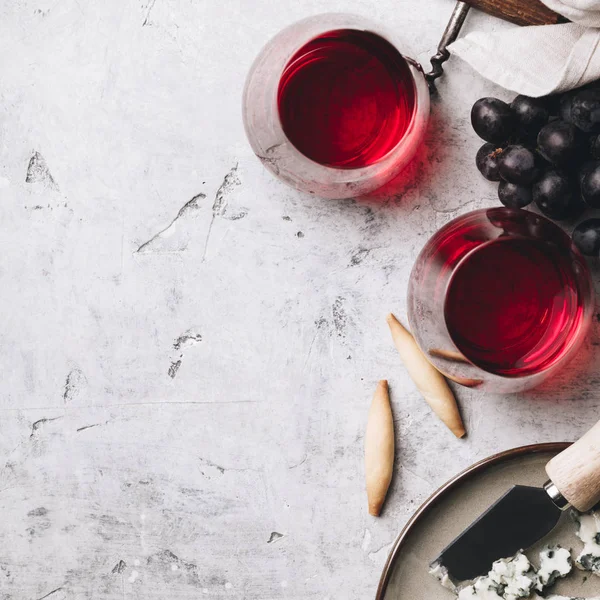 Vasos de vino tinto, queso y uvas sobre hormigón rústico backgr —  Fotos de Stock