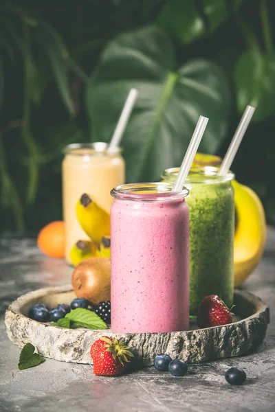 Fresh smoothies on tropical background, close up