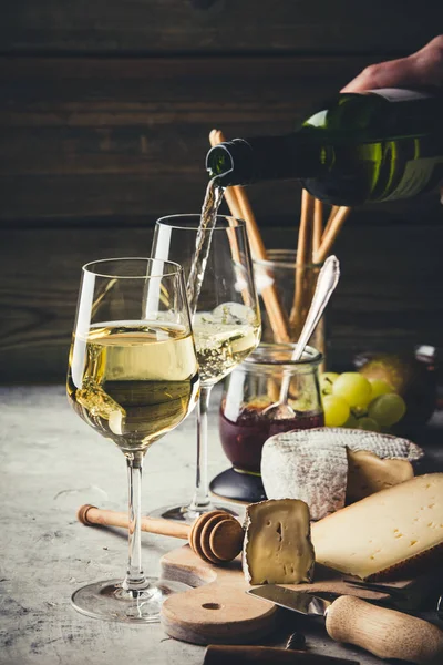 White wine pouring into glasses with charcuterie assortment — 스톡 사진