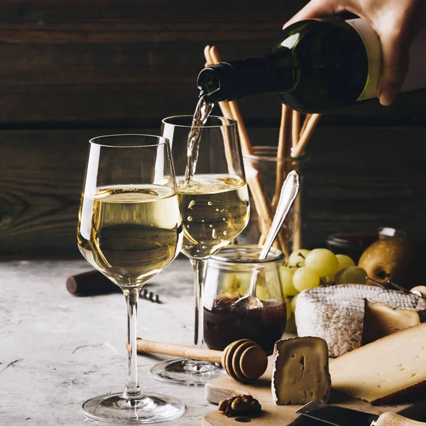 White wine pouring into glasses with charcuterie assortment — 스톡 사진
