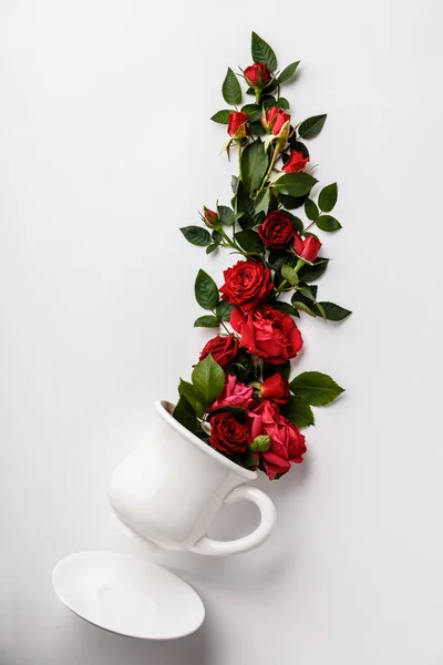 Diseño creativo hecho de café o taza de té con rosas rojas en whit —  Fotos de Stock