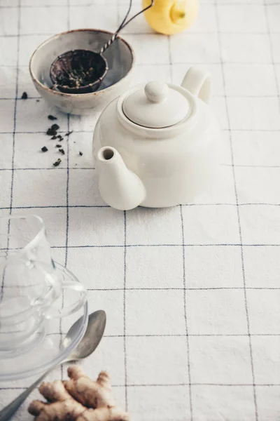 Bule branco, copos e coador na toalha de mesa quadriculada — Fotografia de Stock