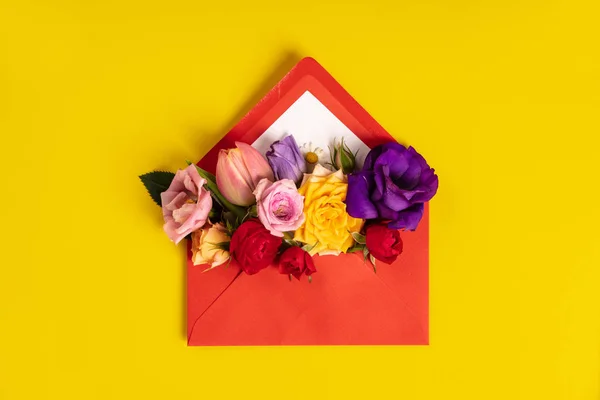 Öppnat rött kuvert med blomsterarrangemang på gul bakgrund — Stockfoto