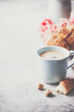 Açık gri arka planda sabah kahvesi, kruvasan ve bahar laleleri