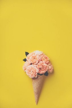 Sarı arka planda pembe güller ile dondurma konisi