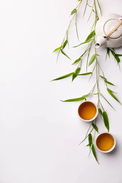 Ensemble de fond alimentaire asiatique avec thé vert, tasses et théière avec des branches de bambou — Photo