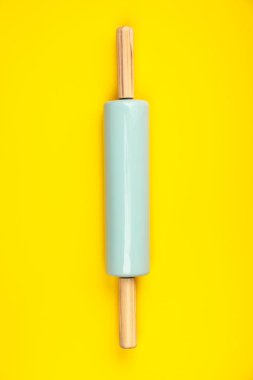 Sarı arka plan üzerinde mavi oklava, düz yatıyordu