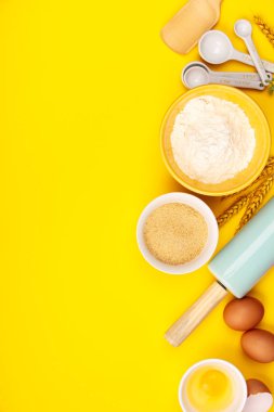 Sarı arka planda pişirme veya pişirme malzemeleri, düz yatıyordu