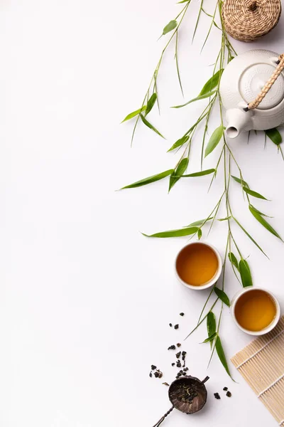 Ensemble de fond alimentaire asiatique avec thé vert, tasses et théière avec des branches de bambou — Photo