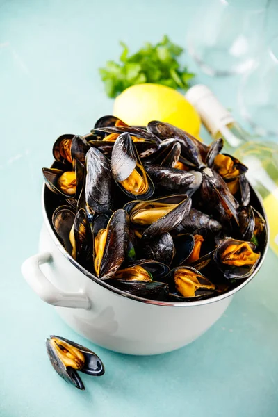 Pot of steamed mussels with lemon, herbs and white wine on blue background — Stock Photo, Image