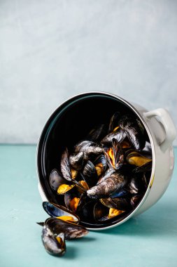 Mavi arka plan üzerinde buğulanmış midye pot