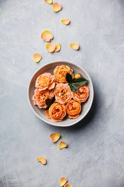 Rosas anaranjadas flotando en el agua sobre fondo de hormigón, SPA y concepto de relajación — Foto de Stock