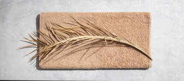 Beton zeminde kurumuş palmiye yaprağı ve havlu.