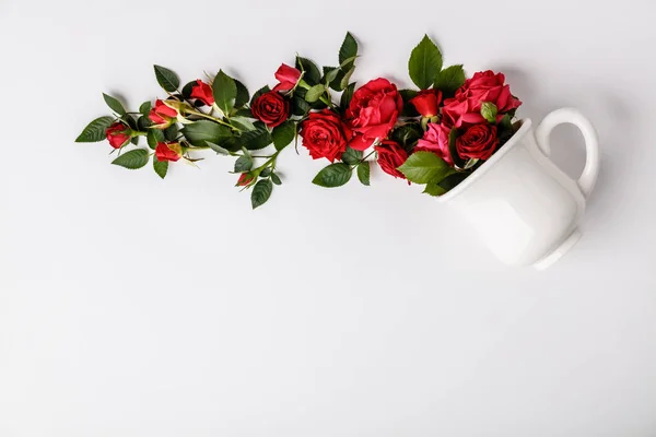 Layout creativo fatto di caffè o tazza di tè con rose rosse su sfondo bianco — Foto Stock