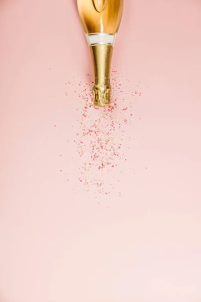 Piatto di celebrazione. Bottiglia di champagne con spruzzi su sfondo rosa . — Foto Stock