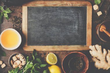 Kırsal arka planda çay kompozisyonu: çay, nane, limon, zencefil.