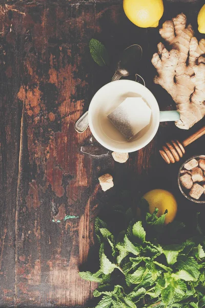 Composizione del tè su sfondo rustico: tè, menta, limone, zenzero . — Foto Stock