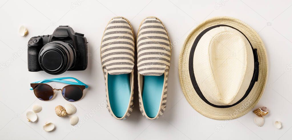 Flat lay traveler accessories on white background with palm leaf, camera and sunglasses