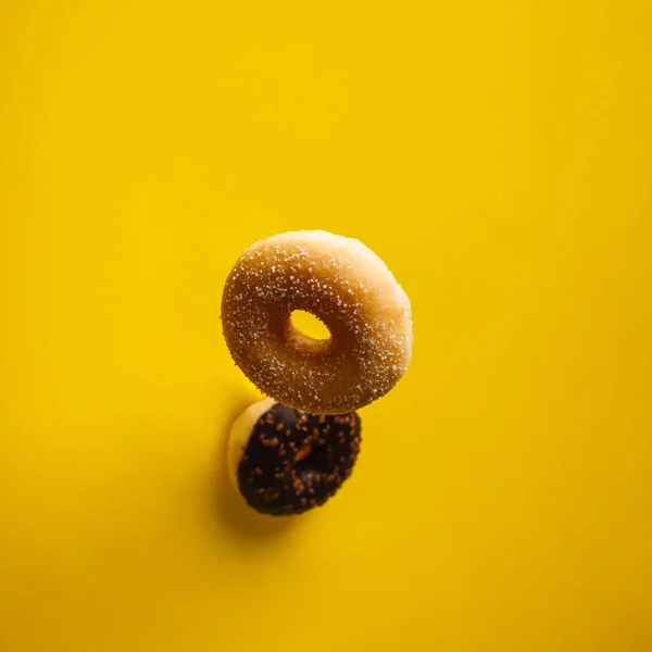 노란 배경 위로 떨어지는 다양 한 장식을 한 도넛 — 스톡 사진