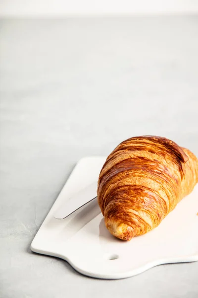 Fresh croissant on white ceramic board, close up — Stock Photo, Image