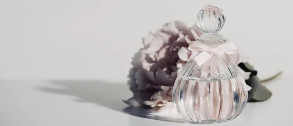 Pink peopy flower and perfume bottle against white wall, copy space — Stock Photo, Image