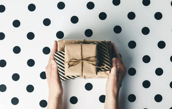 Flat lay arrangement females hands holding gift boxes on white polka dots background — Stock Photo, Image