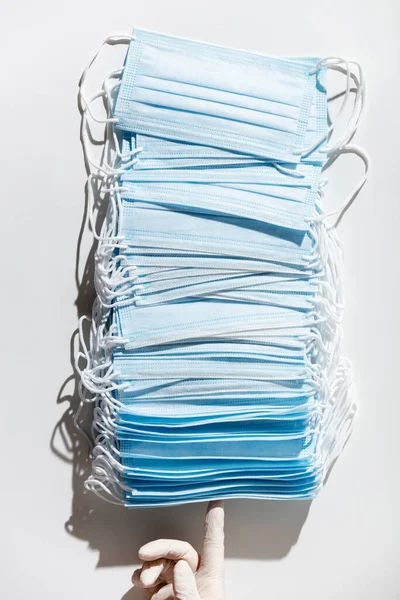 Woman hands in latex gloves holding a stack of facial medical masks, white background, close up — Stock Photo, Image