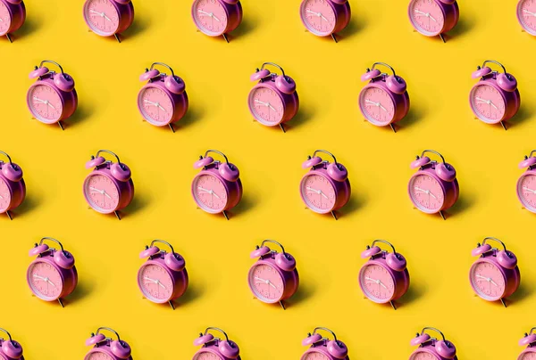 Creatieve lay-out van roze wekker klokken op pastelgele achtergrond. Minimaal concept. — Stockfoto