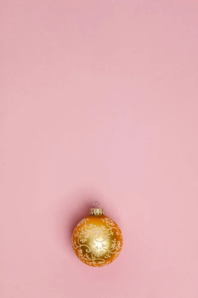 Złota świąteczna piłka na różowym tle. Układy płaskie — Zdjęcie stockowe