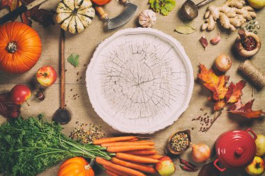 Taze bahçe havuçları, balkabakları, soğanlar, elmalar ve baharatlar kırsal arka planda, ortada ahşap tepsi, üst manzara, kopyalama alanı