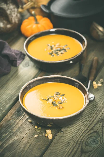 Zuppa di zucca in ciotole su tavolo di legno, cottura e concetto autunnale — Foto Stock