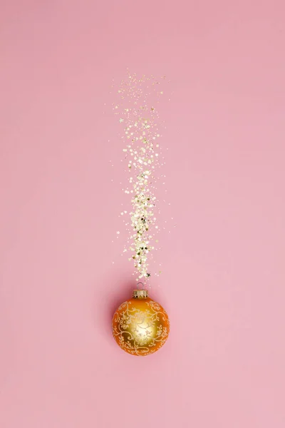 Composizione creativa con palla di Natale e coriandoli di stelle dorate su sfondo rosa — Foto Stock