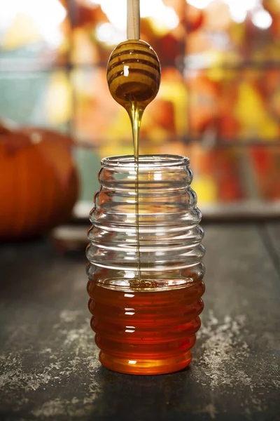 Conceito de outono quente e confortável. Frasco de mel e abóboras no peitoril da janela de madeira — Fotografia de Stock