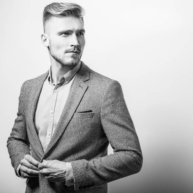 Zarif yakışıklı genç gri ceketli poz studio arka planı. Siyah-beyaz fotoğraf.