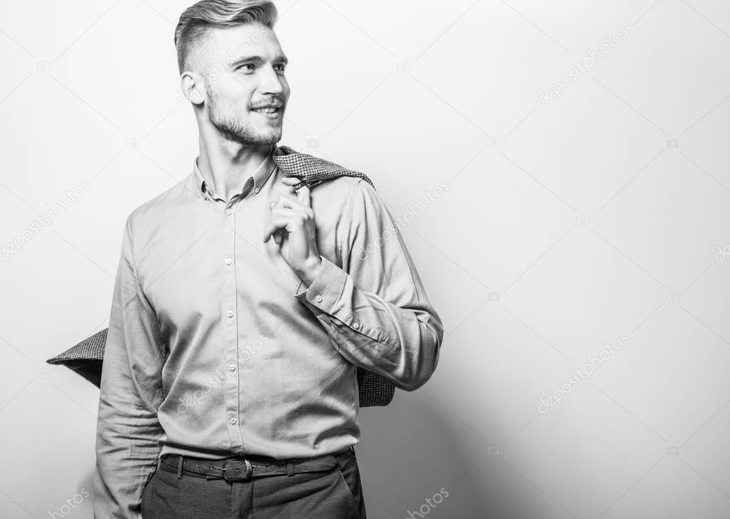 Handsome young elegant man in grey jacket pose against studio background. Black-white photo.
