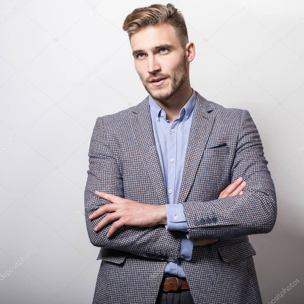 Handsome young elegant man in grey jacket pose against studio background. 
