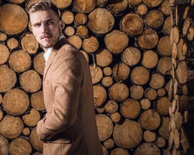Genç güzel moda ceket adam, ahşap arka plan karşı portresi.