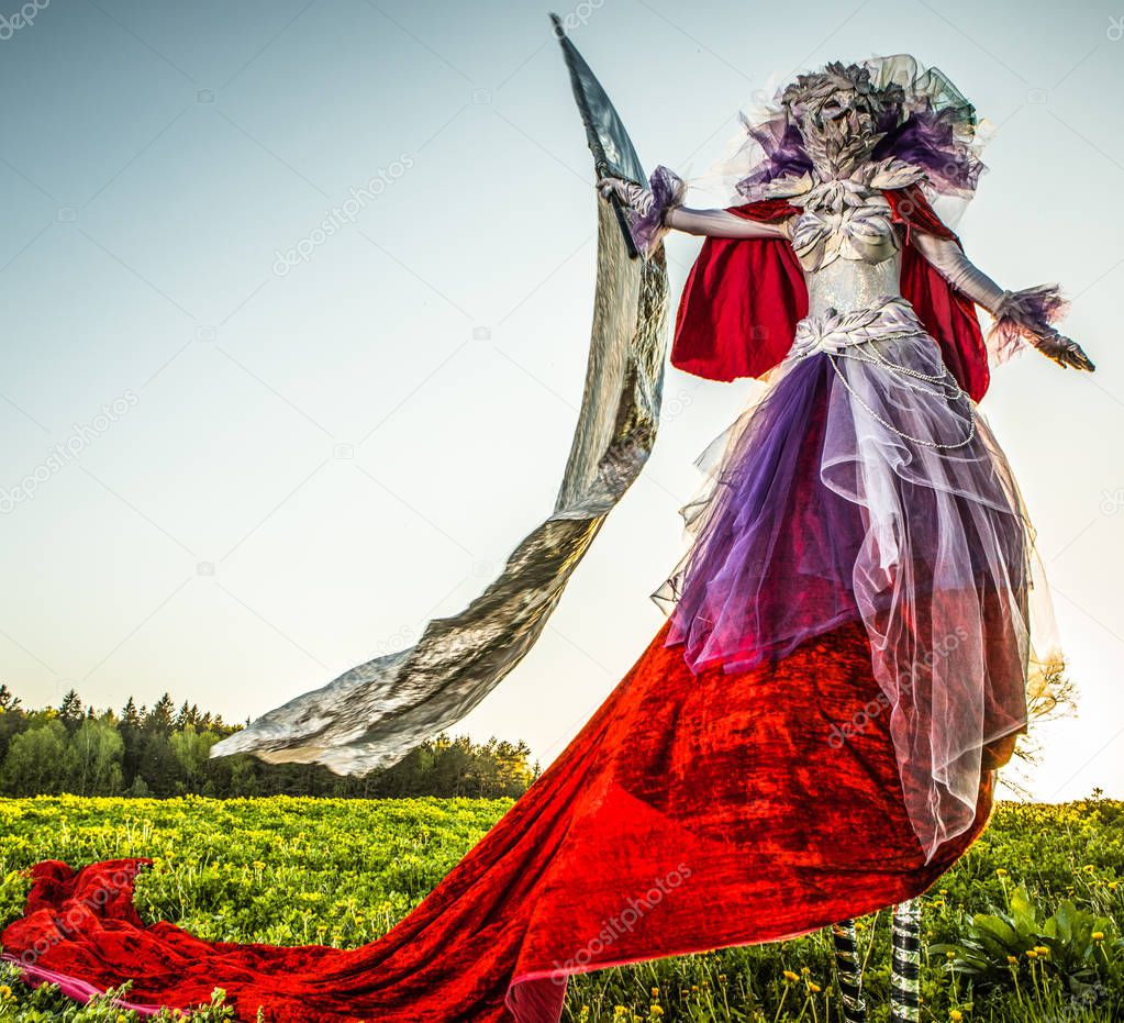 Fairy tale woman on stilts with silver flag in bright fantasy stylization. Fine art outdoor photo. 