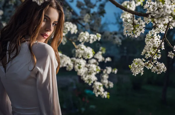 美丽的年轻女子画像在秋季花园反对盛开的樱桃的白色礼服 — 图库照片