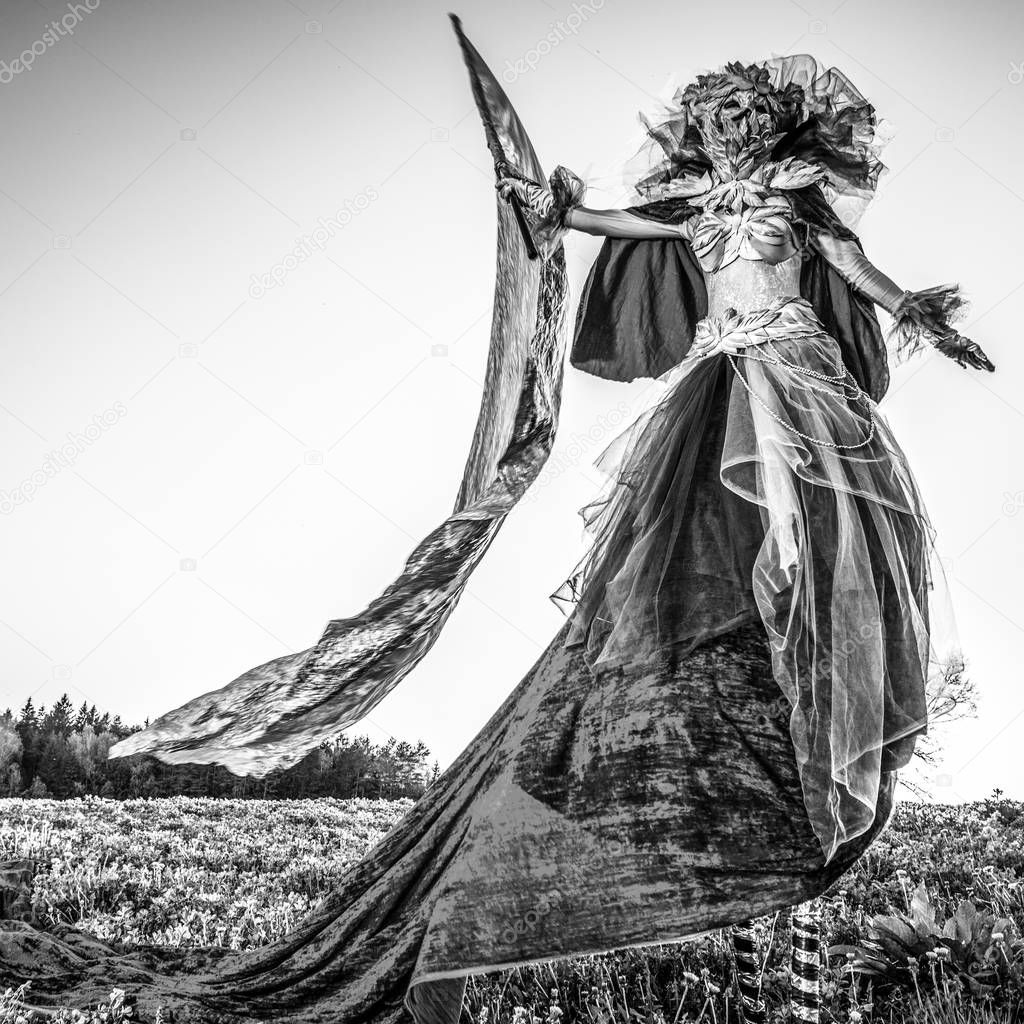 Fairy tale woman on stilts with silver flag in fantasy stylization. Fine art black-white photo. 