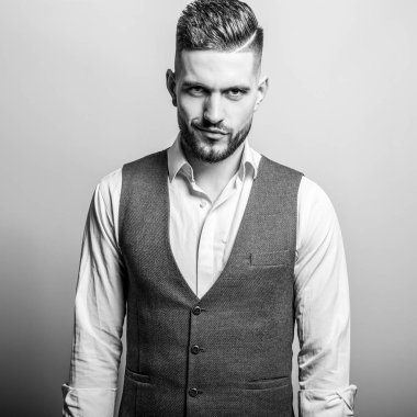 Zarif yakışıklı genç gri klasik yelek içinde poz studio arka planı.