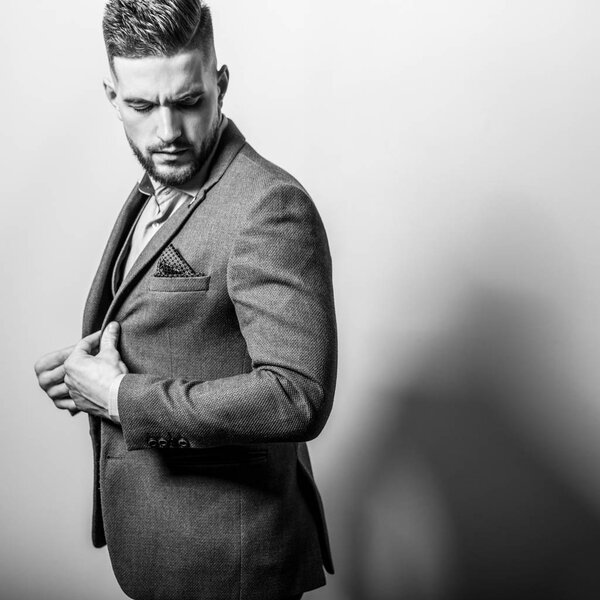 Handsome young elegant man in grey jacket pose against studio background.