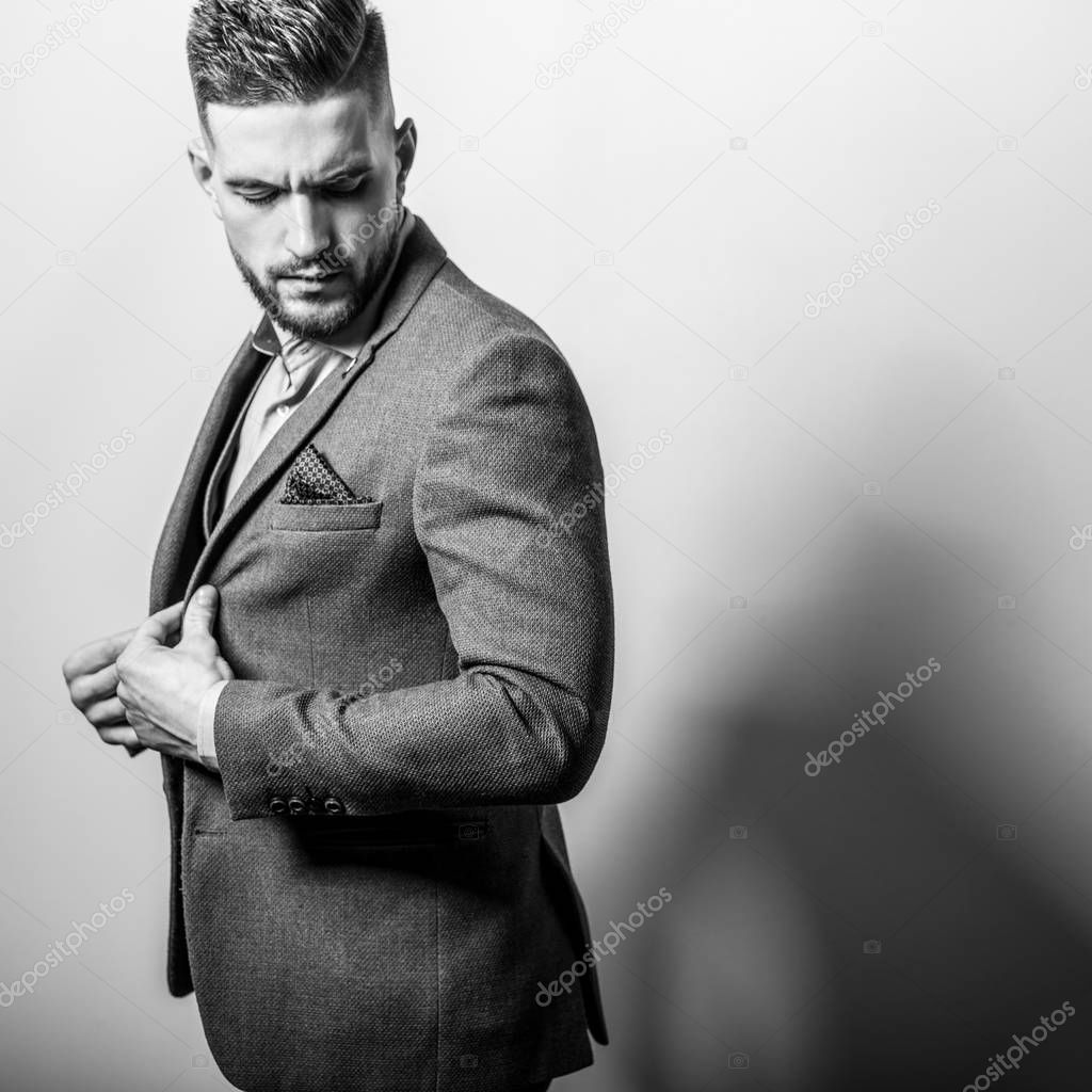 Handsome young elegant man in grey jacket pose against studio background.