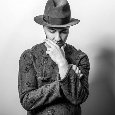 Şık yakışıklı genç uzun palto ve şapka. Siyah-beyaz fotoğraf.