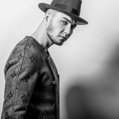 Şık yakışıklı genç uzun palto ve şapka. Siyah-beyaz fotoğraf.