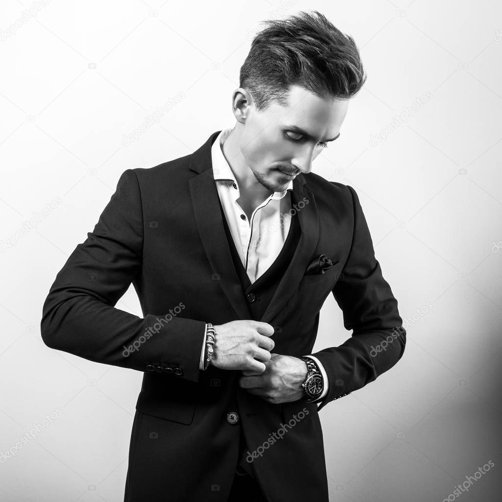 Handsome young elegant man in black stylish classic costume. Black-white photo.