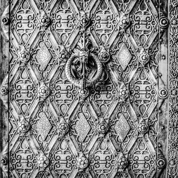 Texture of metal antic door close-up as background. Black-white photo.